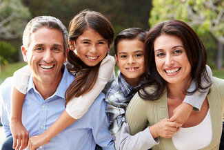 family outside posing for photo smiling, mom dad and two kids. Family Dentistry in Plain City, OH